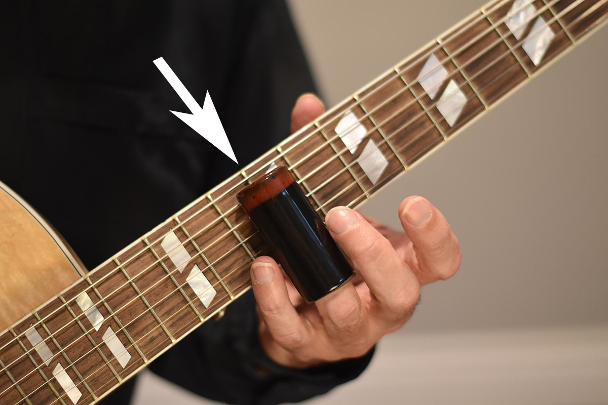 When playing the slide guitar, the musician wears a slide tube on the